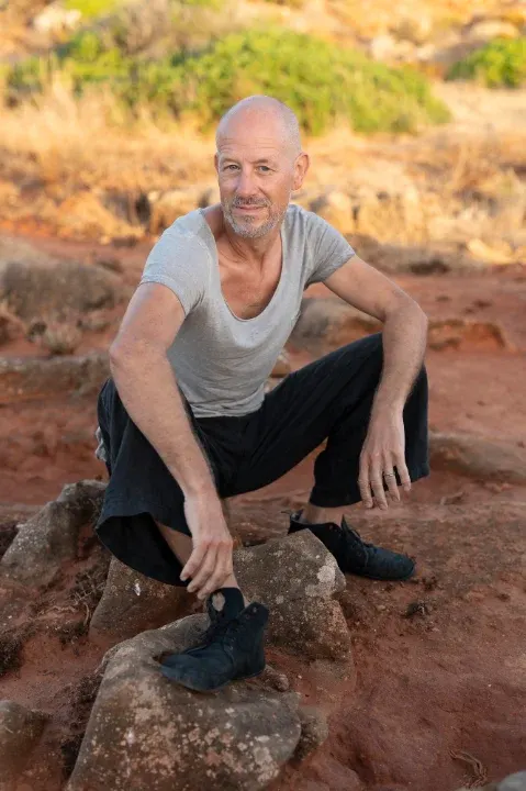Marc Grönnebaum sitzt auf einem Felsen in rötlicher Landschaft